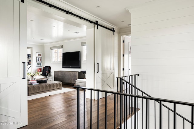 hallway with ornamental molding, wood finished floors, an upstairs landing, and a barn door