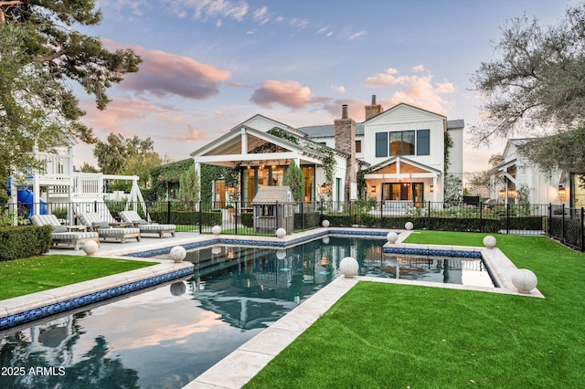 back of house featuring a fenced in pool, a patio, a chimney, fence, and a yard