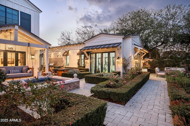 back of house featuring a patio, metal roof, a standing seam roof, french doors, and outdoor lounge area