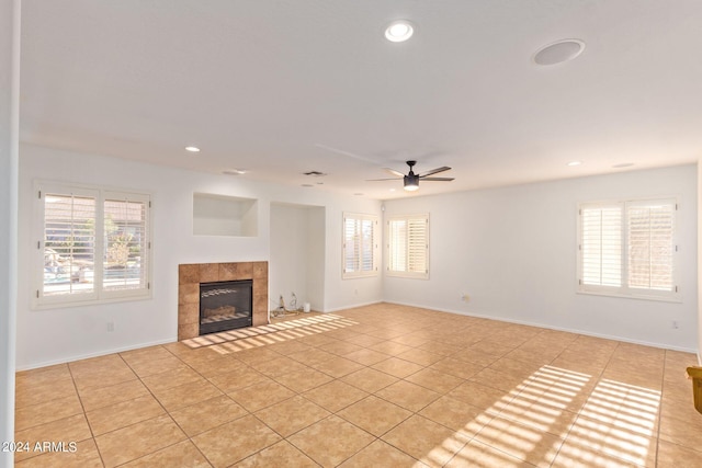 unfurnished living room featuring a tiled fireplace, light tile patterned floors, and ceiling fan