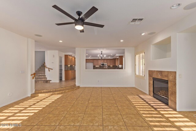 unfurnished living room with a fireplace, light tile patterned floors, and ceiling fan