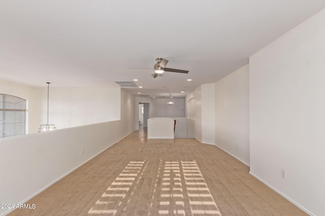 carpeted empty room featuring ceiling fan with notable chandelier