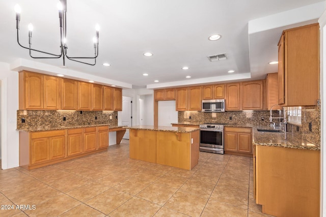 kitchen featuring sink, stone countertops, a center island, stainless steel appliances, and a notable chandelier