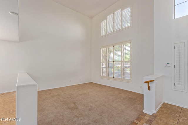 unfurnished living room with a towering ceiling and light carpet