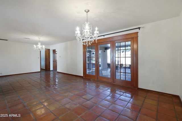 spare room featuring dark tile patterned flooring, an inviting chandelier, and french doors