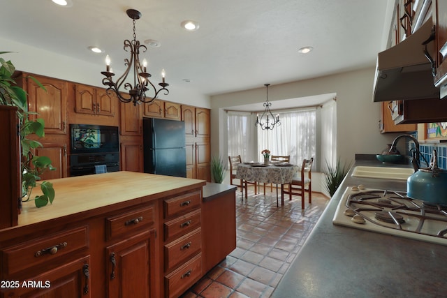 kitchen with wood counters, decorative light fixtures, sink, a notable chandelier, and black appliances