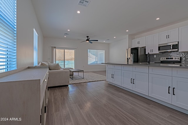 kitchen featuring tasteful backsplash, appliances with stainless steel finishes, light wood-type flooring, and white cabinets