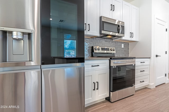 kitchen featuring white cabinetry, backsplash, appliances with stainless steel finishes, and light wood-type flooring