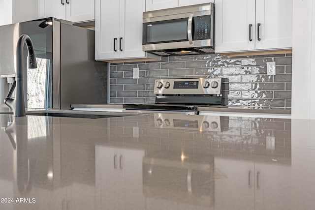 kitchen featuring white cabinets, stainless steel appliances, sink, and backsplash