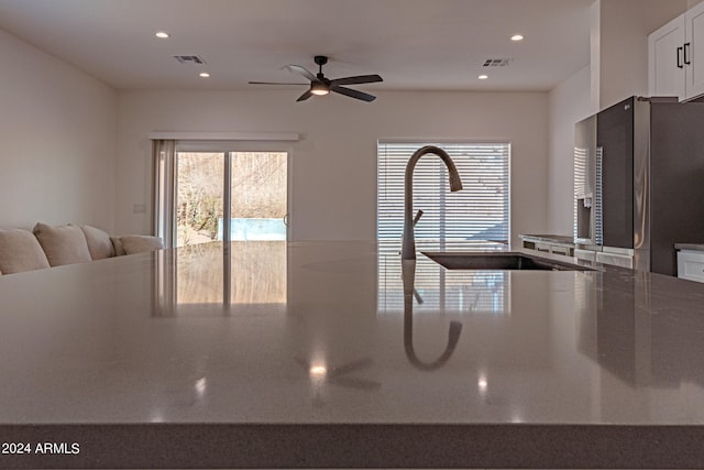 kitchen featuring white cabinetry, ceiling fan, stainless steel refrigerator, and sink