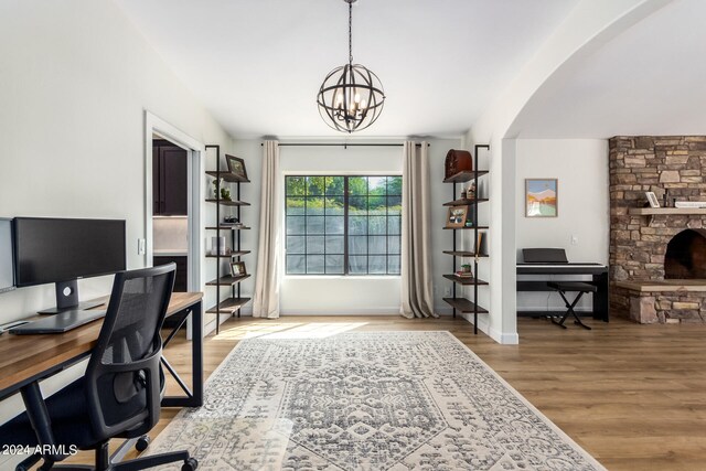 office space with a notable chandelier, a fireplace, and hardwood / wood-style floors