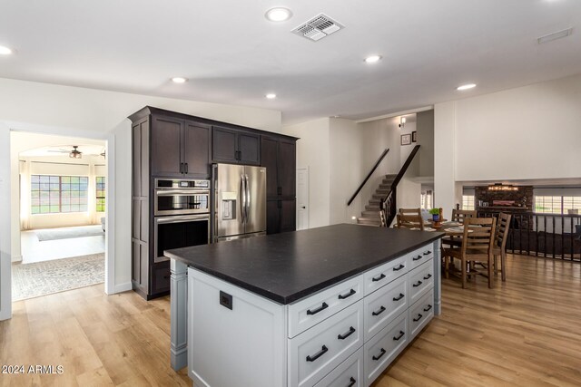 kitchen with ceiling fan, appliances with stainless steel finishes, a center island, and light hardwood / wood-style flooring