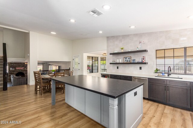 kitchen featuring a brick fireplace, a wealth of natural light, a center island, sink, and dishwasher