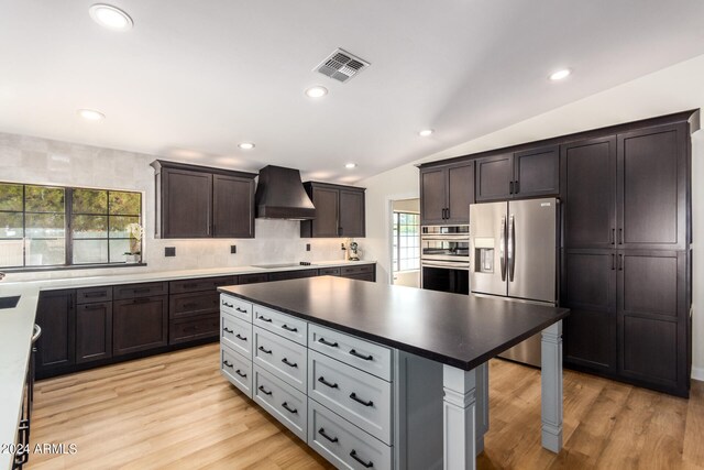 kitchen featuring custom range hood, appliances with stainless steel finishes, lofted ceiling, and a healthy amount of sunlight