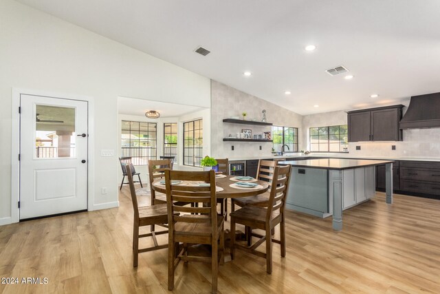 dining area featuring sink, vaulted ceiling, and light hardwood / wood-style floors