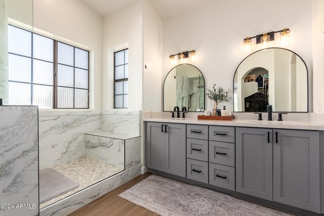 bathroom with wood-type flooring, vanity, a shower, and tile walls