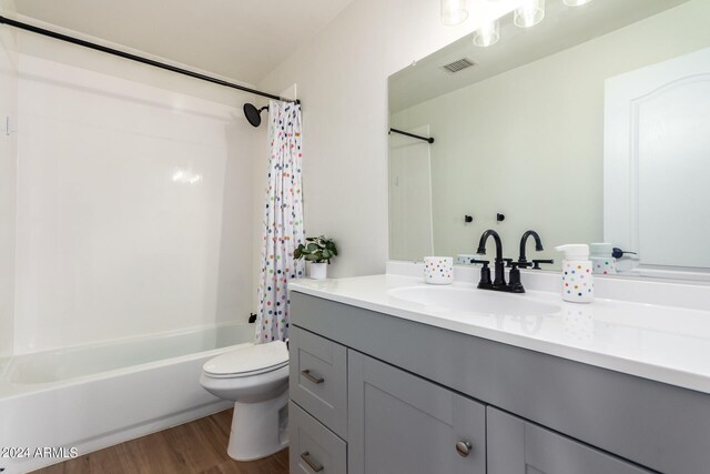 full bathroom with hardwood / wood-style flooring, toilet, shower / tub combo with curtain, and vanity