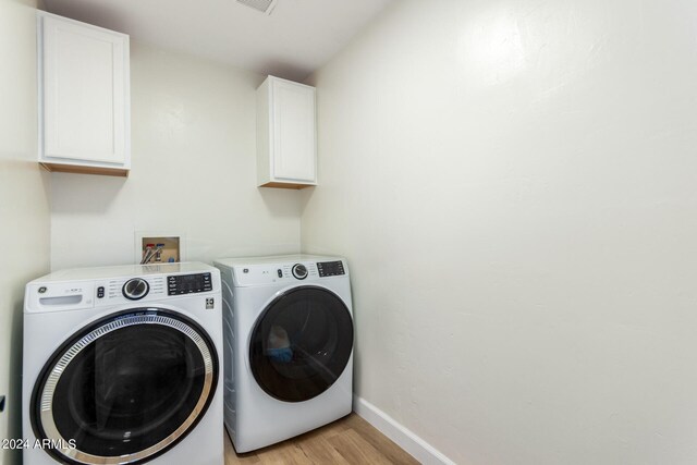 washroom featuring cabinets, light hardwood / wood-style floors, and washer and dryer