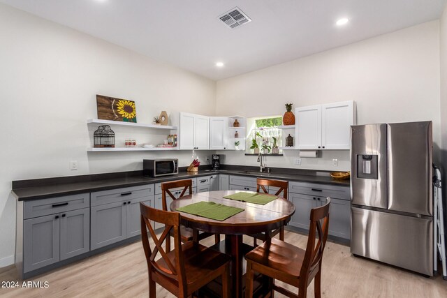 kitchen with light wood-type flooring, gray cabinetry, sink, stainless steel appliances, and white cabinetry