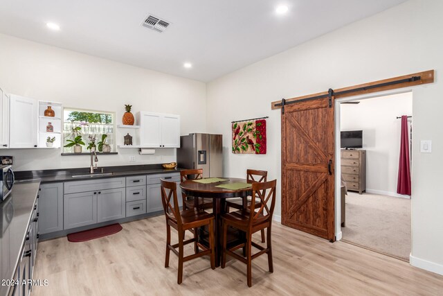 dining area featuring a barn door, light hardwood / wood-style floors, and sink