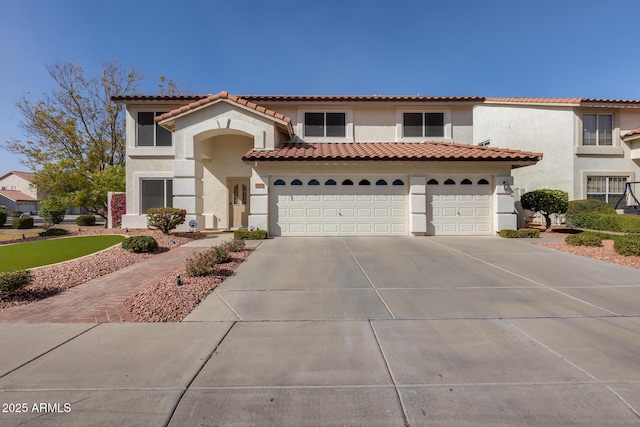 mediterranean / spanish-style home featuring a garage, concrete driveway, a tiled roof, and stucco siding