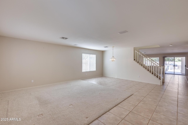 empty room with visible vents, light tile patterned flooring, a wealth of natural light, and baseboards