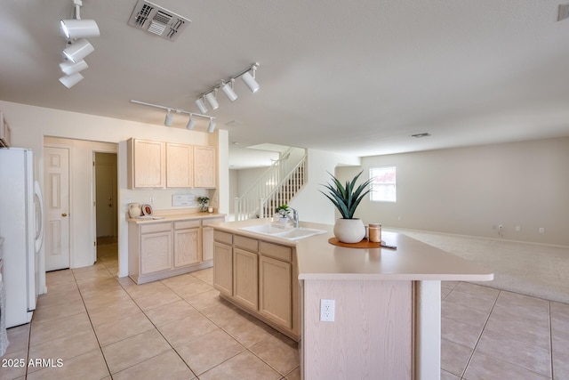 kitchen featuring visible vents, open floor plan, freestanding refrigerator, light brown cabinets, and a sink