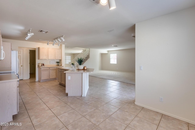 kitchen with light tile patterned floors, visible vents, open floor plan, light brown cabinets, and a sink