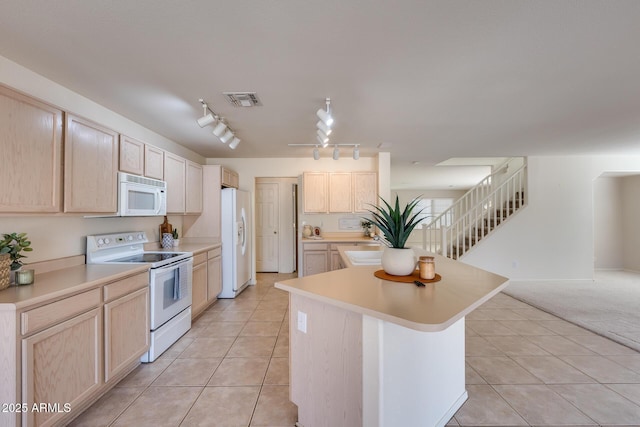 kitchen with light brown cabinetry, white appliances, visible vents, and a center island