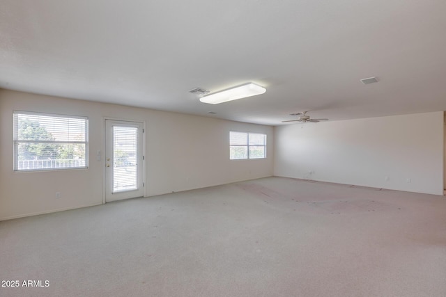 empty room with a ceiling fan, visible vents, and light colored carpet