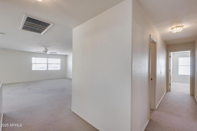 corridor featuring baseboards, visible vents, and carpet flooring