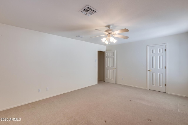 spare room with a ceiling fan, visible vents, light carpet, and baseboards