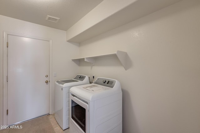 laundry room featuring laundry area, visible vents, washer and dryer, and light tile patterned flooring