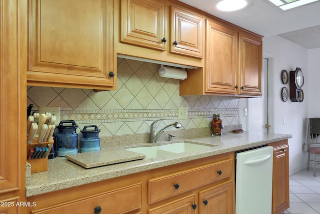 kitchen with tasteful backsplash, sink, light tile patterned floors, and light stone countertops