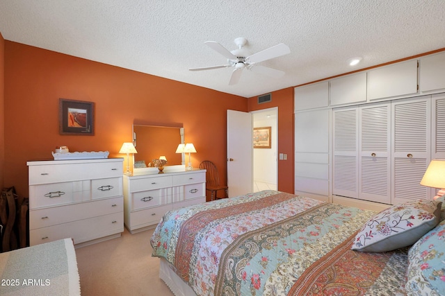 bedroom featuring ceiling fan, a closet, light carpet, and a textured ceiling