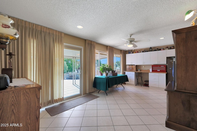 kitchen with ceiling fan, refrigerator, white cabinetry, a textured ceiling, and light tile patterned flooring