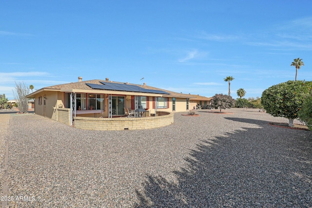 rear view of house with a patio and solar panels