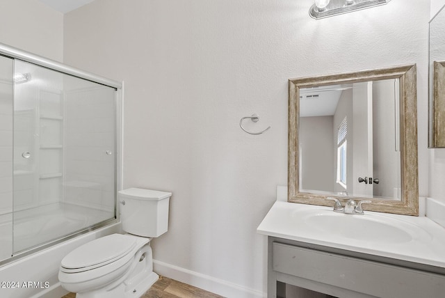 full bathroom with hardwood / wood-style flooring, toilet, vanity, and shower / bath combination with glass door