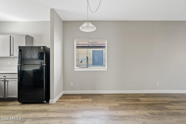 kitchen featuring light hardwood / wood-style flooring, black fridge, gray cabinetry, and hanging light fixtures