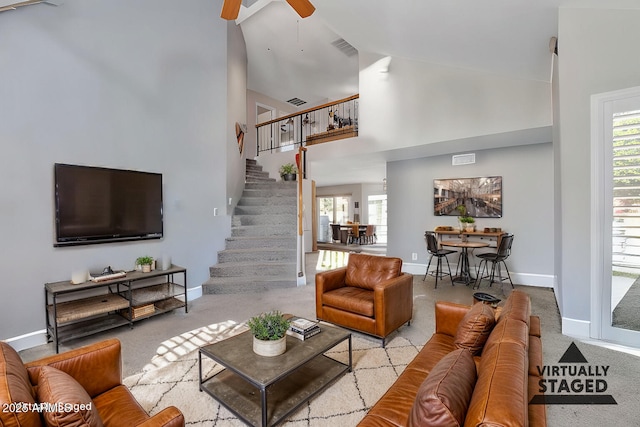 carpeted living room featuring ceiling fan, a towering ceiling, and a healthy amount of sunlight