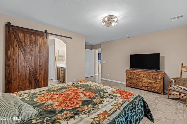 bedroom featuring a barn door and connected bathroom