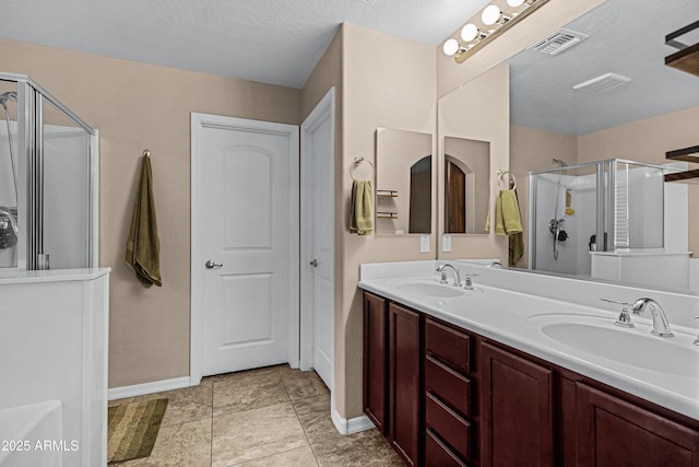 bathroom featuring tile patterned flooring, a textured ceiling, vanity, and a shower with door