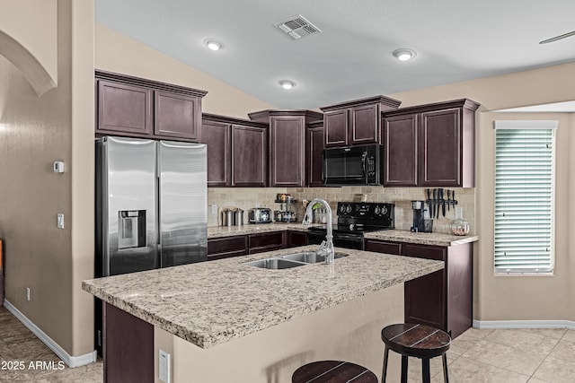 kitchen featuring sink, an island with sink, vaulted ceiling, and black appliances