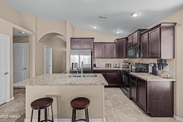 kitchen with lofted ceiling, backsplash, a kitchen island with sink, black appliances, and sink