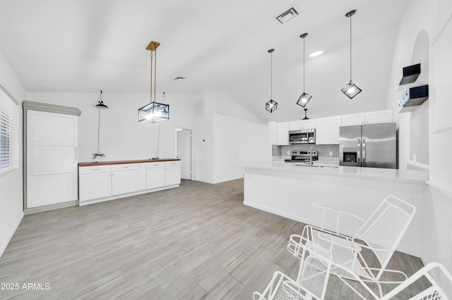3201 W Mohawk Ln, Phoenix, AZ 85027 - kitchen featuring appliances with stainless steel finishes, lofted ceiling, tasteful backsplash, white cabinets, and a peninsula