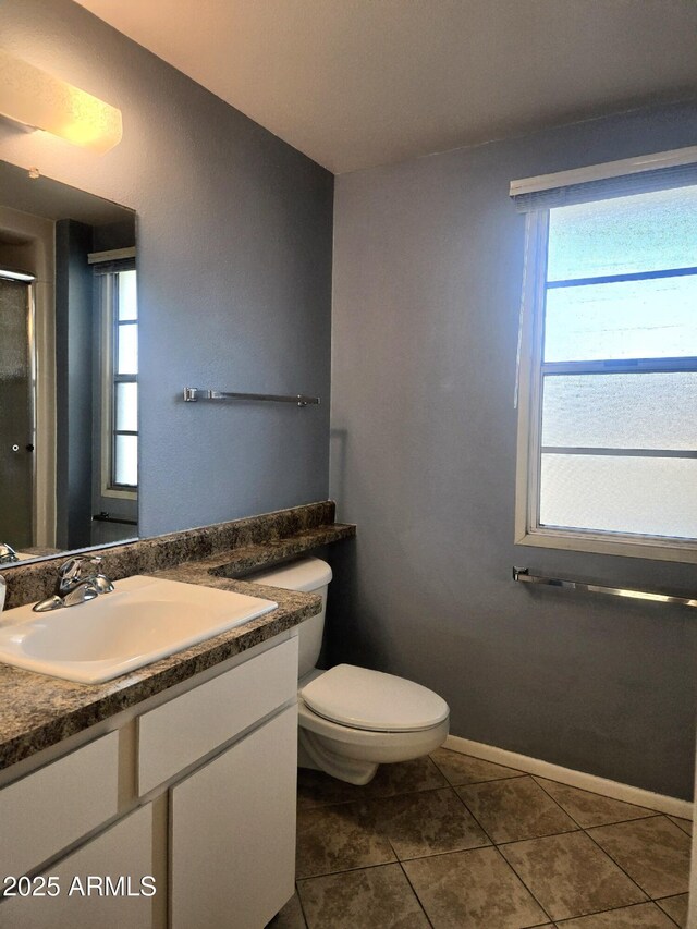 full bath featuring tile patterned flooring, toilet, a healthy amount of sunlight, and vanity