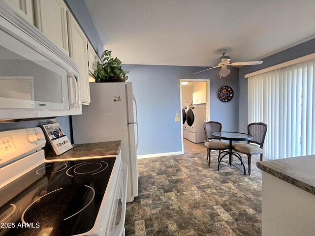kitchen with dark countertops, white appliances, washer and clothes dryer, and a ceiling fan