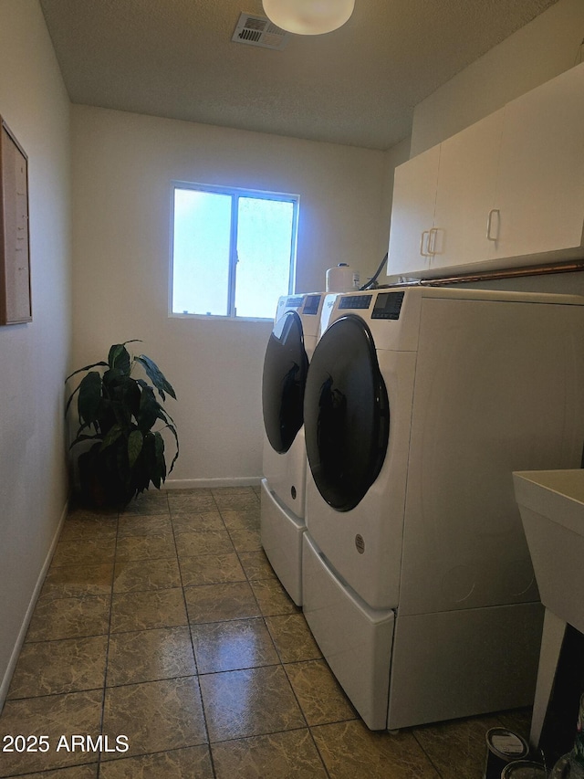 laundry room with baseboards, visible vents, washer and dryer, and cabinet space