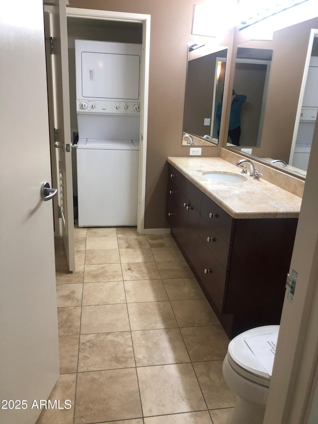 bathroom with toilet, vanity, tile patterned floors, and stacked washer / drying machine