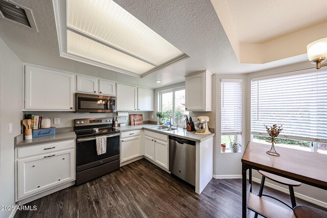 7110 N 28th Dr, Phoenix, AZ 85051 - kitchen with appliances with stainless steel finishes, a sink, white cabinetry, dark wood-style flooring, and baseboards